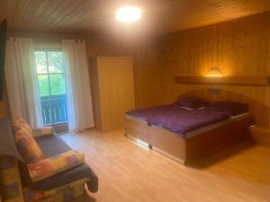 ein Schlafzimmer mit einem Bett und einem Stuhl in einem Zimmer in der Unterkunft Pension Maximilian in Gamlitz