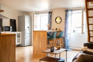 cocina y sala de estar con nevera y mesa en Appartement au Centre ville historique Le vieux Langres, en Langres