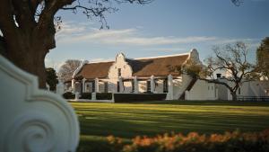 a large white house with a grass yard at Vergenoegd Löw Boutique Hotel & Spa in Cape Town