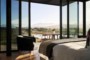 a bedroom with a bed and a table and windows at Vergenoegd Löw Boutique Hotel & Spa in Cape Town +88 photos