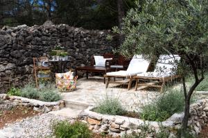 d'une terrasse avec des chaises et un mur en pierre. dans l'établissement Fisherman's house La Pineta, à Murter