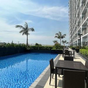 a swimming pool with tables and chairs next to a building at CozyCoastStay by APPLETRAVELBEYONDPH in Manila