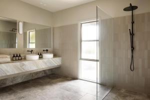 La salle de bains est pourvue de 2 lavabos et d'une douche en verre. dans l'établissement Carrajung Estate, à Willung South