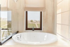 baño con bañera blanca y ventana en Chateau Purcari, en Purcari