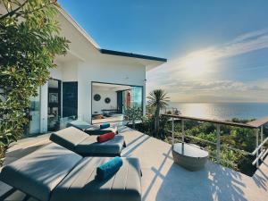 un patio con sofá, sillas y el océano en VILLA TSAY - Nature, Privacy, Elegance, en Haad Yao
