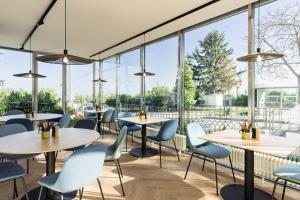 un restaurante con mesas, sillas y ventanas grandes en Bio-Hotel Schani Wienblick en Viena