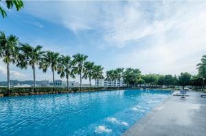 a swimming pool with palm trees and a blue sky at NC Cottage @ The Loft Imago in Kota Kinabalu