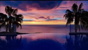 una puesta de sol sobre el océano con palmeras y una piscina en VISTA SUPERIOR hola ZEEZICHT!! en Cumbre del Sol