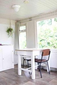 Natuurhuisje Veluwe met houtkachel en pizzaoven في إرميلو: طاولة بيضاء وكراسي في غرفة مع نافذة