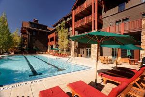 una piscina con sillas y sombrillas junto a un hotel en The Ritz Carlton Residences Aspen en Aspen