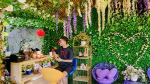 um homem sentado numa sala com uma parede de flores em Homestay Sala em Ho Tram