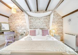 a bedroom with a large white bed with pink pillows at Dowr Penty in Helford