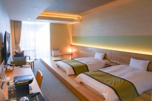 熱海市にあるISHINOYA 熱海 / 石のや 熱海のベッド2台とデスクが備わるホテルルームです。