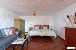 1 dormitorio con 1 cama y 1 sofá azul en Living Artenara - CAVE HOUSE & SILENCE Adults Only, en Artenara