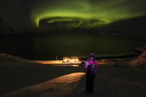 eine Person, die einen unbefestigten Weg unter der Aurora entlang geht in der Unterkunft Nordmannsneset på Seiland in Hammerfest