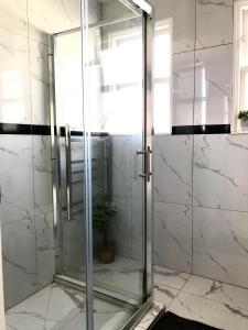 a glass shower door in a bathroom with a plant at Santos Place in Auckland