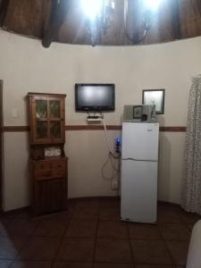 een keuken met een koelkast en een tv aan de muur bij Harties Lodge - Private Suite in Hartbeespoort
