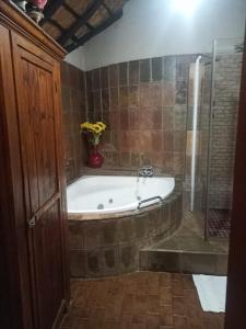 een badkamer met een bad en een vaas met bloemen bij Harties Lodge - Private Suite in Hartbeespoort