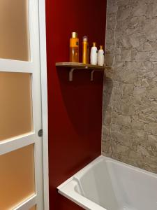 La salle de bains est pourvue d'une baignoire blanche et d'un mur rouge. dans l'établissement Appartement Le O'mehr, à Saint-Omer