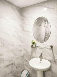 a white bathroom with a sink and a mirror at Cityscape Grand Tower Condominium in Cebu City