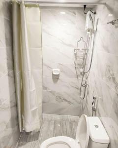 a white bathroom with a toilet and a shower at Cityscape Grand Tower Condominium in Cebu City