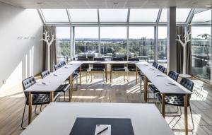 een grote kamer met tafels en stoelen en grote ramen bij First Hotel Planetstaden in Lund