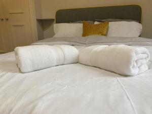 dos toallas blancas sentadas encima de una cama en MMR Flats en Carlisle