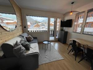 uma sala de estar com um sofá e uma mesa em Bel appartement rénové, central et skis aux pieds em Morzine