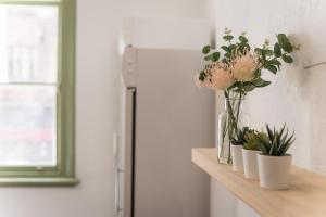 un jarrón de flores en un estante junto a un refrigerador en Sydney Central Inn en Sídney