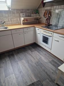 a kitchen with white cabinets and a wooden floor at Melle Ferienwohnung in Melle