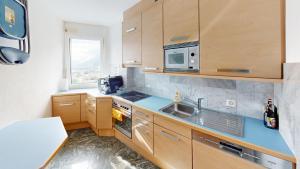 a kitchen with wooden cabinets and a sink and a microwave at Über den Dächer von Chur (Calanda) in Chur