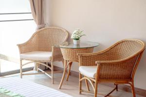 twee rieten stoelen en een glazen tafel met een tafel bij Eco Hotel by Thammasat in Bang Lamung