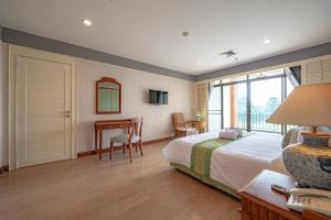 a bedroom with a bed and a desk and a table at Eco Hotel by Thammasat in Bang Lamung