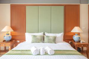 a bedroom with a large bed with two lamps and two beds sidx sidx at Eco Hotel by Thammasat in Bang Lamung