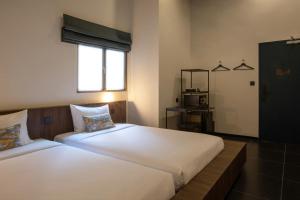 a bedroom with two beds and a window and a mirror at Beanstalk Bangkok in Bangkok