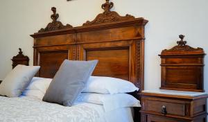 a bed with a wooden head board and white pillows at ABBAZIA SS. QUIRICO E GIULITTA in Micigliano