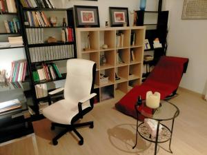 una sala de estar con una silla blanca y un estante para libros. en Alameda Donkey Parking, en Sevilla
