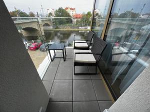 d'un balcon avec des chaises, une table et une rivière. dans l'établissement Apartman Champion III, à Plzeň