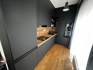 Il comprend une cuisine avec des murs noirs et du parquet. dans l'établissement Apartman Champion III, à Plzeň