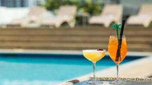 two cocktails sitting on a table next to a pool at Pacific Hotel Cairns in Cairns