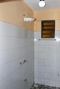 a bathroom with a white tiled shower with a window at Airport Bliss House in Kisumu