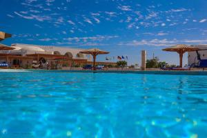 Beach safari nubian resort في مرسى علم: مسبح كبير به ماء ازرق ومظلات