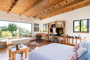 a bedroom with a large window and a tub and a bed at Granite Forest Chalet in Cape Town
