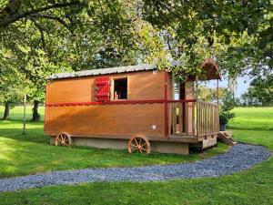 le cocon d'amour " Roulotte avec bain nordique privée" في La Chapelle-du-Fest: كابينة خشبية صغيرة في حقل عشبي