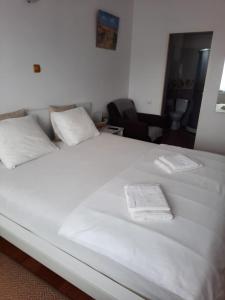 a large white bed with two white towels on it at Pensiunea Corbeanca - cazare si evenimente in Corbeanca
