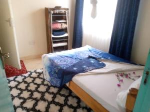 a bedroom with a bed with a blue sheet on it at Pelia Rose Guesthouse in Kisumu