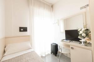a bedroom with a bed and a desk with a television at Hotel Saint Louis in Rimini