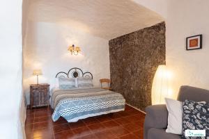 um quarto com uma cama e um sofá em Living Artenara - CAVE HOUSE & TERRACE Adults Only em Artenara