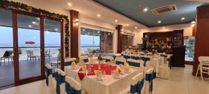 um salão de banquetes com mesas e cadeiras brancas e o oceano em Hai Duong Intourco Resort, Vung Tau em Vung Tau