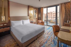 a bedroom with a bed and a living room with a desk at Doubletree By Hilton Antalya City Centre in Antalya